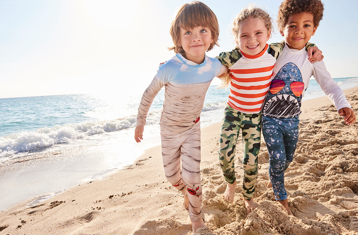 Green Camo 2pc Rash Guard Set UPF50 and Sunny Crab 2pc Rash Guard Set UPF50 and Shark 2pc Rash Guard Set Kids on the beach hugging wearing sun protective clothing sunpoplife